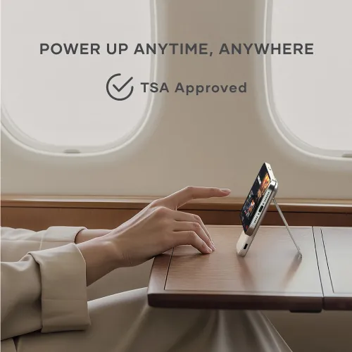 Satechi magnetisk powerbank med stativ, der holder en smartphone oprejst på et flybord