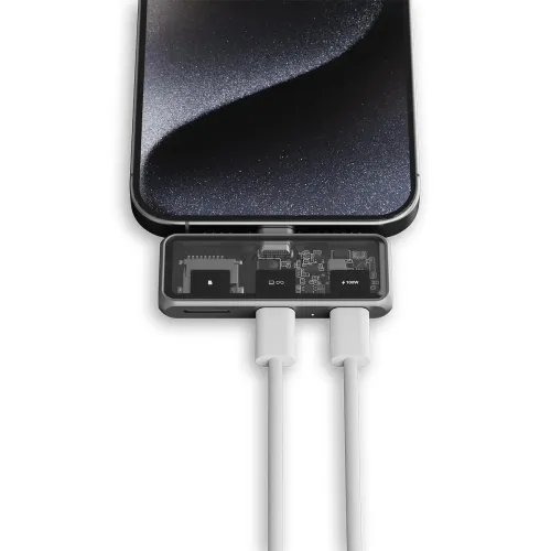"Satechi Mobile XR Hub" po išmaniuoju telefonu; permatomoje viršutinėje dalyje matyti microSD lizdas ir spausdintinė plokštė, prijungti du USB-C kabeliai.