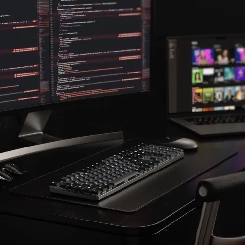 Satechi SM3 mekanisk Bluetooth-tastatur i mørk utførelse med bakgrunnsbelysning og lav profil på skrivebordsmatte ved siden av musen.