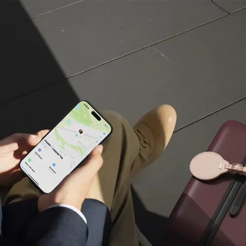 Vegaaninahkainen Satechi FindAll -matkatavaralappu matkalaukussa, ja Apple Find My -seuranta näkyy älypuhelimessa