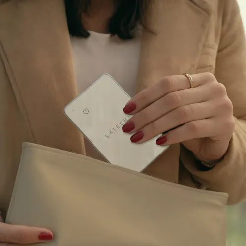 "Satechi FindAll" smėlio spalvos piniginė kortelė; plona, kreditinės kortelės dydžio, užapvalintais kampais, su mažu šviesos diodu ir maitinimo piktograma, įdėta į smėlio spalvos dėklą.