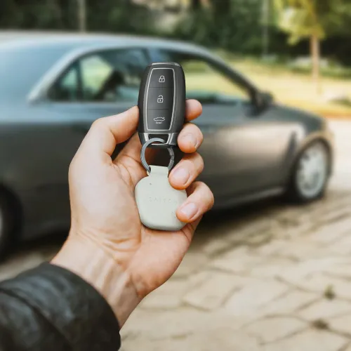 "Satechi" raktų pakabukas iš smėlio spalvos veganiškos odos su suapvalintu kvadratiniu pakabuku ir įspaustu logotipu ant metalinio žiedo su automobilio rakteliu.