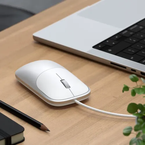 Satechi Slim LX-mus med kabel på ett skrivbord med en laptop, som visar tyst, exakt scrollning och en låg profil.