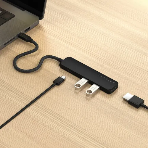 Satechi 4-in-1 USB-C Slim Multiport Adapter, connected to laptop with braided cable, two USB-A flash drives and HDMI cable next to it.