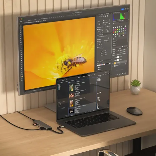 Satechi USB-C 7-in-1 -sovitin, väriltään avaruudenharmaa, työpöydällä, liitettynä kannettavaan tietokoneeseen, HDMI-kaapeli näytölle ja asetettu SD-kortti aktiivisena.