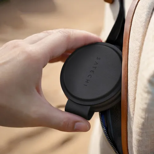 Satechi OntheGo trådløs lader i svart, rund med logo, er håndholdt og skyves inn i en sidelomme på en lys stoffveske.