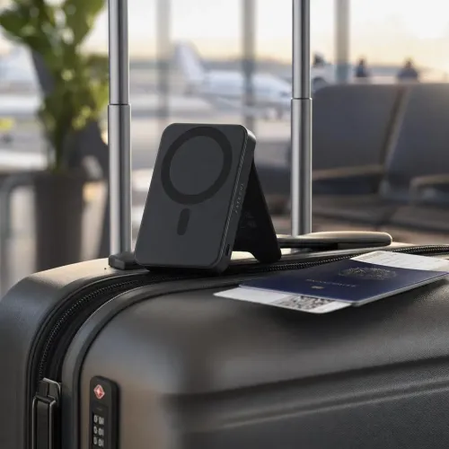 Satechi magnetisk Qi2-powerbank med stand, der oplader på en kuffert i et lufthavnsmiljø