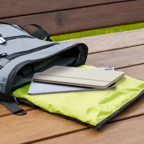 Satechi OntheGo foldbart Bluetooth-tastatur i sandfarve, liggende på en tablet i en åben rygsæk.