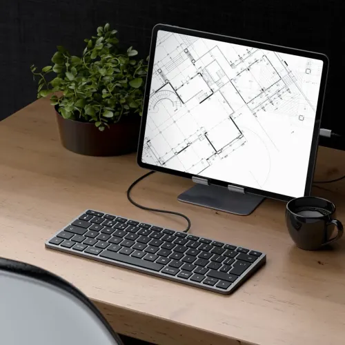 Satechi W1 USB-C-tangentbord på ett skrivbord bredvid en surfplatta, som visar den kompakta trådbundna Mac- och iOS-designen