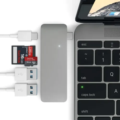 Satechi USB-C-läpivientikeskitin kytkettynä kannettavaan tietokoneeseen, muistikortteja ja USB-A-portteja lähistöllä